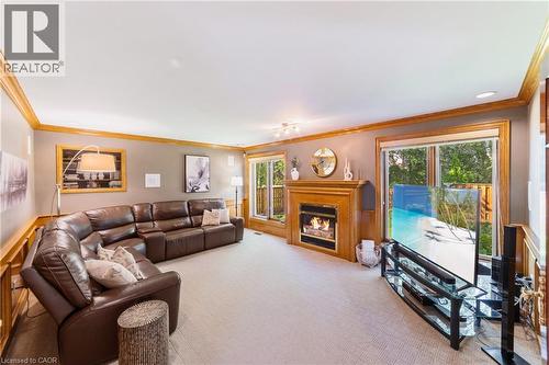 Living room with solid wood crown molding and trim, gas fireplace, in-wall speakers, 2 oversized windows, solid wood wainscoted walls, neutral Berber carpet, intercom, recessed lighting - 7775 St. Augustine Crescent, Niagara Falls, ON - Indoor Photo Showing Living Room With Fireplace