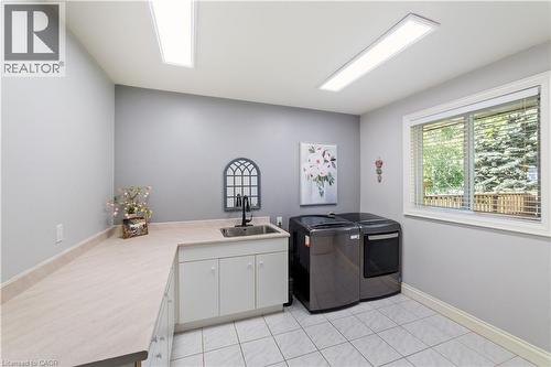 Laundry room on the main floor, large window, cabinets for extra storage, neutral ceramic tiles, extra LED lighting, sink, intercom.  Not show is a large closet opposite the appliances. - 7775 St. Augustine Crescent, Niagara Falls, ON - Indoor Photo Showing Other Room