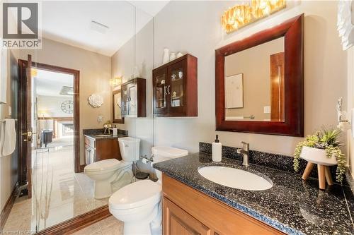 Bathroom on the main level with mirrored wall, solid wood door and trim and granite topped wood vanity - 7775 St. Augustine Crescent, Niagara Falls, ON - Indoor Photo Showing Bathroom