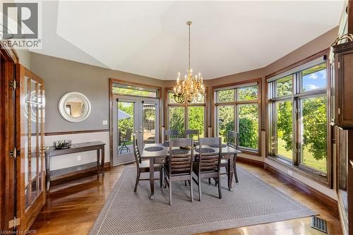 Dining space featuring glass French doors, wood finished floors, a chandelier, lofted ceiling surrounded by expansive windows for lots of natural light - 7775 St. Augustine Crescent, Niagara Falls, ON - Indoor Photo Showing Dining Room