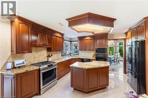 Timeless custom kitchen with black and s/s appliances, built in oven and microwave, dishwasher, gas stove, custom range hood, a center island, neutral backsplash and ceramic floor, granite countertops - 7775 St. Augustine Crescent, Niagara Falls, ON - Indoor Photo Showing Kitchen