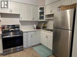 Kitchen with appliances with stainless steel finishes, white cabinets, and glass insert cabinets - 