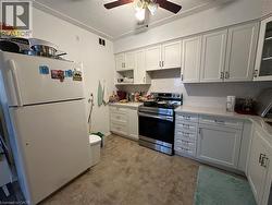 Kitchen with freestanding refrigerator, stainless steel electric range, white cabinetry, and glass insert cabinets - 