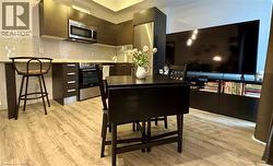 Kitchen with stainless steel appliances, light vinyl flooring, tasteful backsplash, a breakfast bar area, and modern cabinets - 