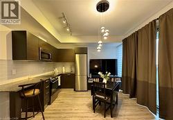 Kitchen featuring light wood finished floors, appliances with stainless steel finishes, modern cabinets, and pendant lighting - 