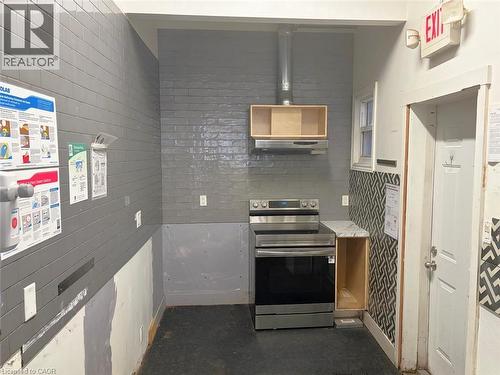 Kitchen with stainless steel range with electric stovetop, open shelves, light countertops, and under cabinet range hood - 175 John Street S, Hamilton, ON 
