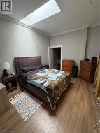 Bedroom with crown molding, a skylight, and wood finished floors - 