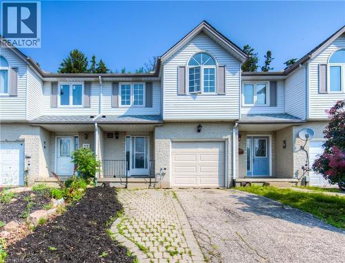Traditional home featuring a porch, asphalt driveway, brick siding, and a garage - 20 Bankside Drive, Kitchener, ON - Outdoor With Facade