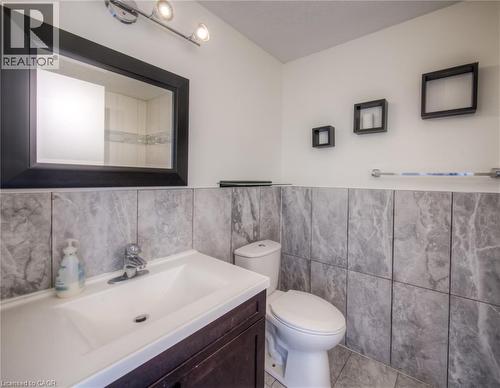 Full bath with vanity, tile walls, a wainscoted wall, and light tile patterned floors - 20 Bankside Drive, Kitchener, ON - Indoor Photo Showing Bathroom