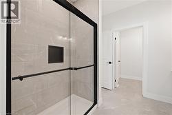 Bathroom featuring a shower stall and light tile patterned flooring - 