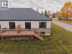Rear view of property with a lawn, a wooden deck, and a shingled roof - 
