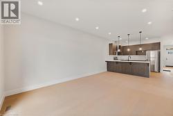 Kitchen featuring modern cabinets, a peninsula, dark brown cabinetry, open floor plan, and stainless steel appliances - 