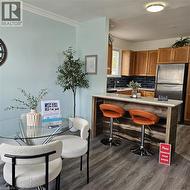 Kitchen with backsplash, dark wood-type flooring, freestanding refrigerator, brown cabinetry, and a kitchen bar - 
