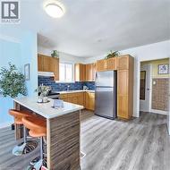 Kitchen featuring stainless steel appliances, a peninsula, light wood-type flooring, brown cabinetry, and a breakfast bar - 