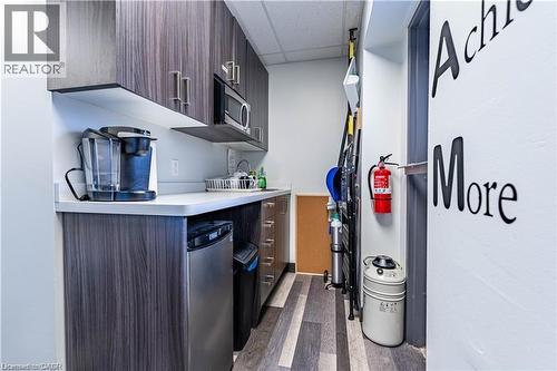 Kitchen with light countertops, a drop ceiling, modern cabinets, dark wood finished floors, and dark brown cabinets - 10 Main Street, Mississauga, ON 