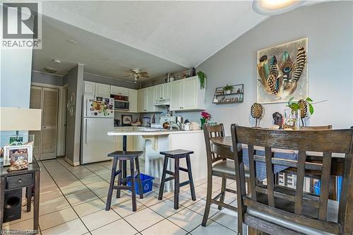 Kitchen with freestanding refrigerator, light tile patterned floors, light countertops, a peninsula, and a ceiling fan - 10 Main Street, Mississauga, ON 