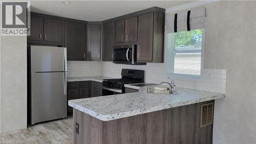 Kitchen featuring stainless steel appliances, dark brown cabinets, decorative backsplash, a peninsula, and light countertops - 24 Macpherson Crescent, Flamborough, ON - Indoor Photo Showing Kitchen With Upgraded Kitchen