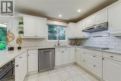Kitchen with white cabinets, light stone counters, black appliances, open shelves, and light tile patterned floors - 