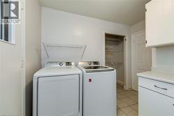 Washroom with light tile patterned floors, cabinet space, and independent washer and dryer - 