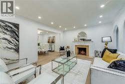 Living area with crown molding, a high end fireplace, light wood-style flooring, recessed lighting, and arched walkways - 