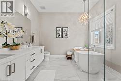 Bathroom featuring a soaking tub, double vanity, light marble finish flooring, and a chandelier - 