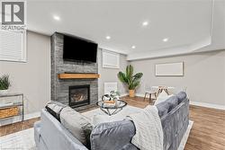 Living room featuring a stone fireplace, wood finished floors, and recessed lighting - 