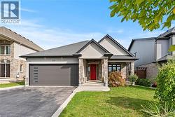 View of front of property with driveway, a front lawn, roof with shingles, and an attached garage - 