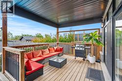 Wooden terrace featuring area for grilling and an outdoor living space - 