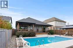 View of swimming pool featuring a patio area, a fenced backyard, and a gazebo - 