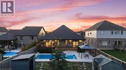 Rear view of property featuring a patio area, a storage unit, a fenced backyard, and a shingled roof - 