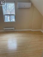 Additional living space with a wall mounted air conditioner, light wood finished floors, a baseboard radiator, and lofted ceiling - 