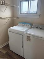 Washroom with dark wood-style floors and washing machine and dryer - 