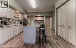 Kitchen featuring light stone countertops, tasteful backsplash, light hardwood / wood-style flooring, a breakfast bar area, and a kitchen island - 