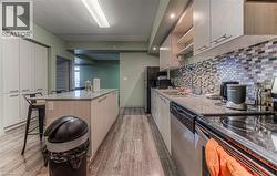 Kitchen with backsplash, light stone counters, a breakfast bar, a textured ceiling, and stainless steel appliances - 