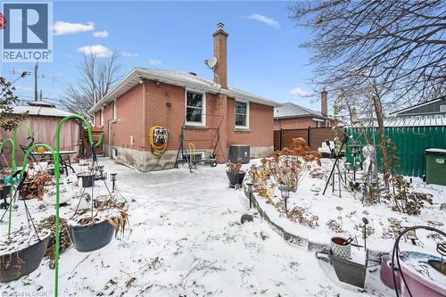 Snow covered rear of property with a fenced backyard, brick siding, a patio area, and a chimney - 263 East 36Th Street, Hamilton, ON - Outdoor