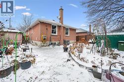 Snow covered rear of property with a fenced backyard, brick siding, a patio area, and a chimney - 