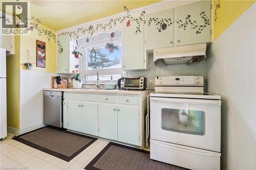 Kitchen with white appliances, light countertops, under cabinet range hood, white cabinetry, and light floors - 263 East 36Th Street, Hamilton, ON - Indoor
