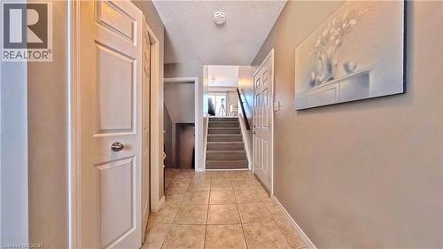 Hallway featuring a textured ceiling, stairway, and light tile patterned flooring - 206 Westmeadow Drive, Kitchener, ON - Indoor Photo Showing Other Room