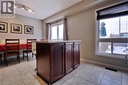 Kitchen with dark brown cabinetry, light tile patterned flooring, light countertops, and a center island - 