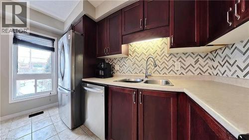 Kitchen with dark brown cabinets, stainless steel appliances, decorative backsplash, and light countertops - 206 Westmeadow Drive, Kitchener, ON - Indoor Photo Showing Kitchen With Double Sink
