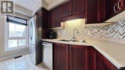 Kitchen with dark brown cabinets, stainless steel appliances, decorative backsplash, and light countertops - 