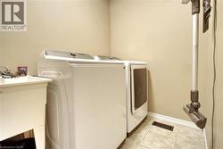 Laundry room with light tile patterned floors and washing machine and dryer - 