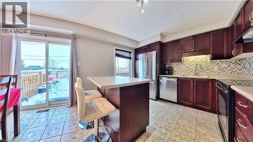 Kitchen with reddish brown cabinets, light tile patterned flooring, appliances with stainless steel finishes, a center island, and a textured ceiling - 206 Westmeadow Drive, Kitchener, ON - Indoor Photo Showing Kitchen With Stainless Steel Kitchen With Double Sink With Upgraded Kitchen