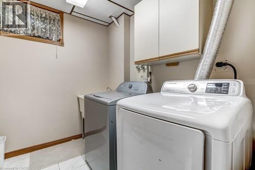 Laundry room with light tile patterned flooring, independent washer and dryer, and cabinet space - 2 Falls Crescent, Simcoe, ON - Indoor Photo Showing Laundry Room