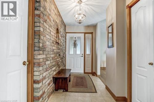 Entryway with a chandelier, tile patterned floors, and brick wall - 2 Falls Crescent, Simcoe, ON - Indoor Photo Showing Other Room