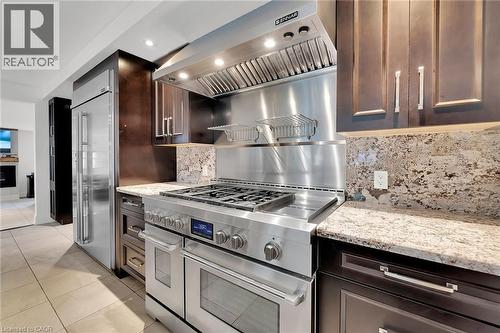 Kitchen featuring exhaust hood, light stone countertops, premium appliances, dark brown cabinetry, and recessed lighting - 404 Mountain Brow Boulevard E, Hamilton, ON - Indoor Photo Showing Kitchen With Upgraded Kitchen
