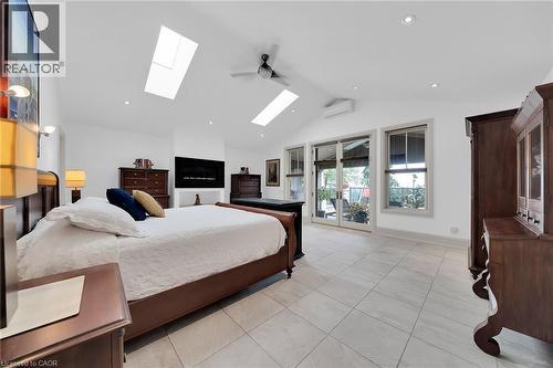 Bedroom featuring vaulted ceiling, access to exterior, a wall mounted air conditioner, light tile patterned flooring, and a skylight - 404 Mountain Brow Boulevard E, Hamilton, ON - Indoor Photo Showing Bedroom