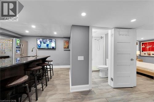 Indoor wet bar featuring recessed lighting, light wood-type flooring, dark countertops, and stainless steel fridge with ice dispenser - 404 Mountain Brow Boulevard E, Hamilton, ON - Indoor