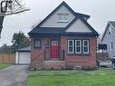 Brick exterior featuring a bright red front door with vertical window panels, black wrought iron railing, and dark trim details - 215 Walter Avenue S, Hamilton, ON  - Outdoor 