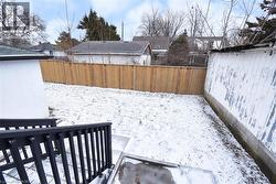 Yard layered in snow featuring a fenced backyard and a wooden deck - 